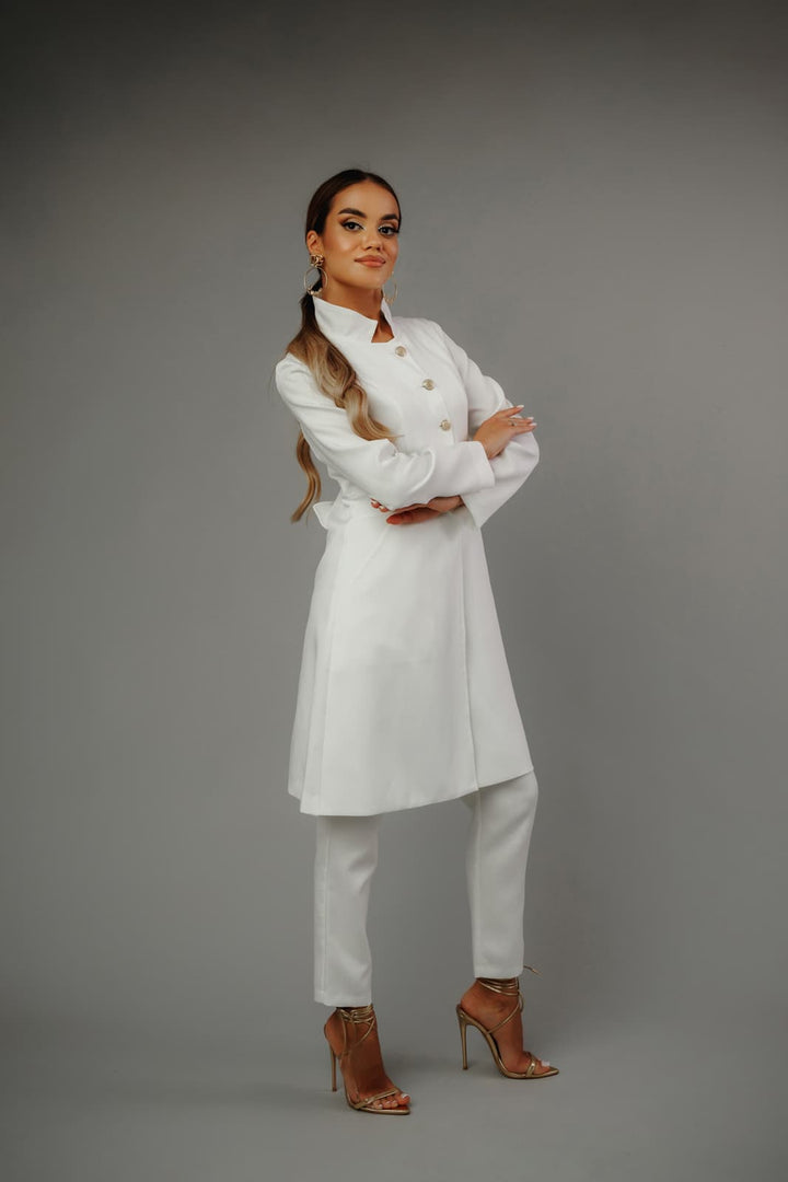 piękna_modelka_w_eleganckim_białym_żakiecie_i_spodniach_MedElite_na_szarym_tle_złote_sandały_dodają_elegancji.