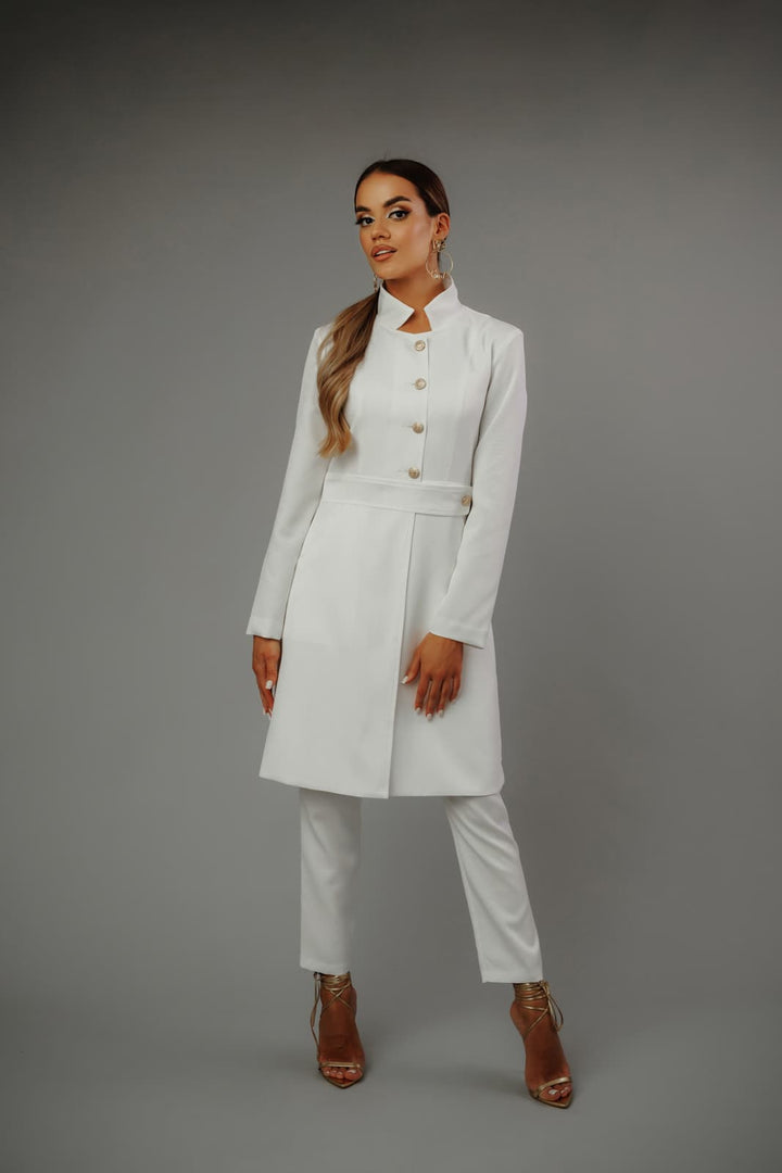 Modelka_w_eleganckim_białym_żakiecie_i_spodniach_MedElite_na_szarym_tle_złote_sandały_dodają_elegancji.